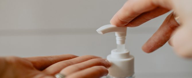 person holding white plastic pump bottle