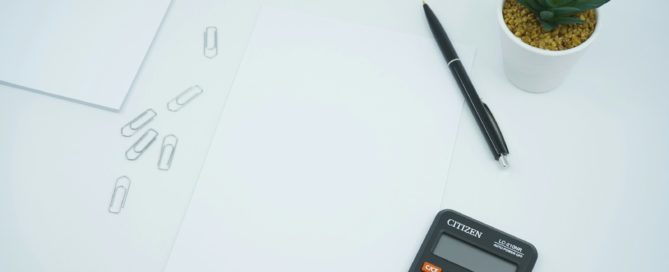 black calculator beside black pen on white printer paper