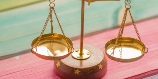 small gold balance scale on colorful wood